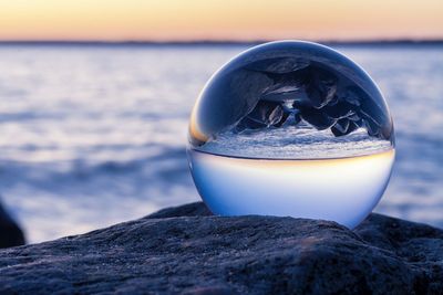 Reflection of beach and sea in crystal ball during sunset