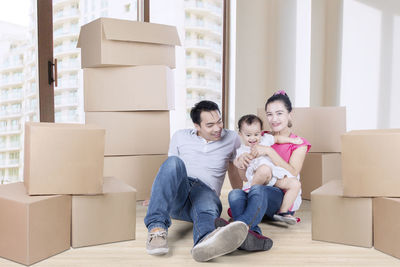 Happy parents and daughter sitting in new home