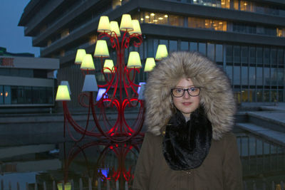 Portrait of girl standing in front of illuminated building