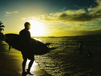 Silhouette man on beach against sky during sunset