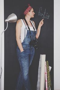 Midsection of young woman standing against wall