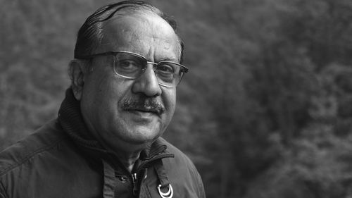 Portrait of man smiling while standing against trees