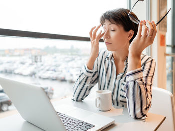 Business woman with laptop in co-working center. workplace for freelancers. female rubs her eyes.