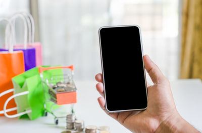 Close-up of hand holding mobile phone on table