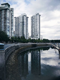 Bridge over river by buildings in city against sky