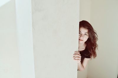 Portrait of woman standing against wall