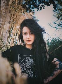 Portrait of beautiful young woman against trees