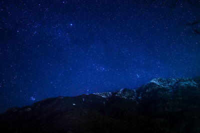 Low angle view of mountain against star field at night