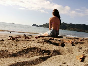 Rear view of woman on shore at beach against sky