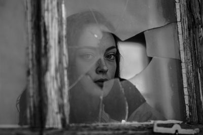 Portrait of woman seen through cracked window glass