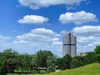 Trees and buildings on field against sky