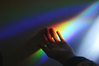 Cropped hand of man with prism by wall