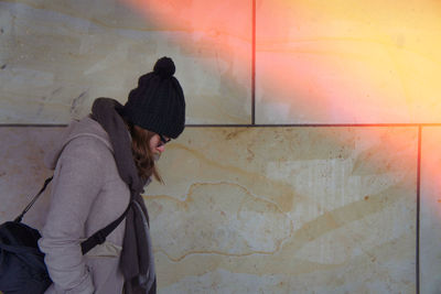 Side view of woman standing against wall