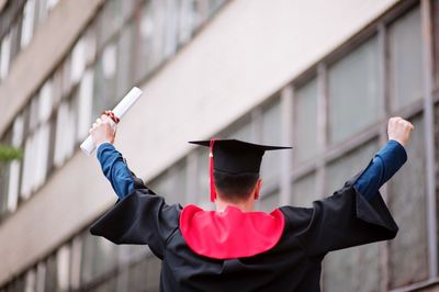 Man holding hat while standing against built structure