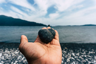 Close-up of hand holding sea against sky