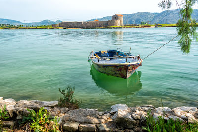 Boat moored on lake against sky