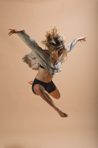 Full length of young woman jumping over white background