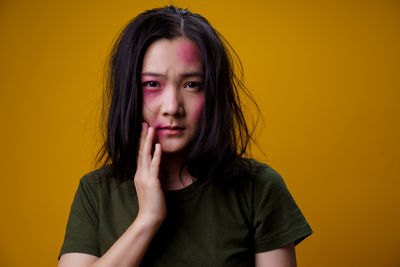 Portrait of beautiful young woman against yellow background