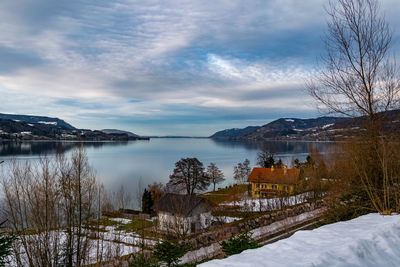 Scenic view of lake by snowcapped mountains against sky