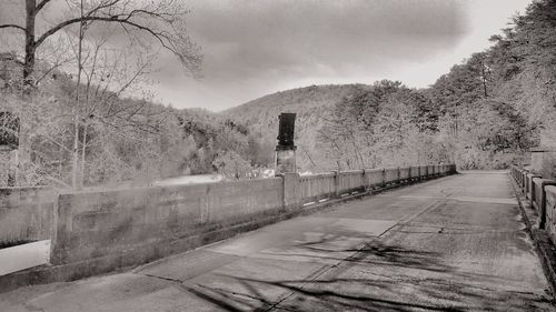 Road amidst bare trees against sky