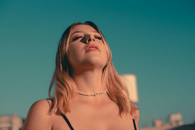 Low angle view of young woman against blue sky