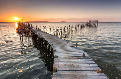 Wooden pier on sea against sky during sunset