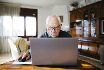 Portrait of serious looking senior man using laptop at home