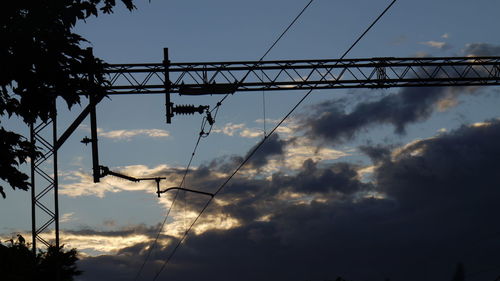 Low angle view of silhouette electricity pylon against sky