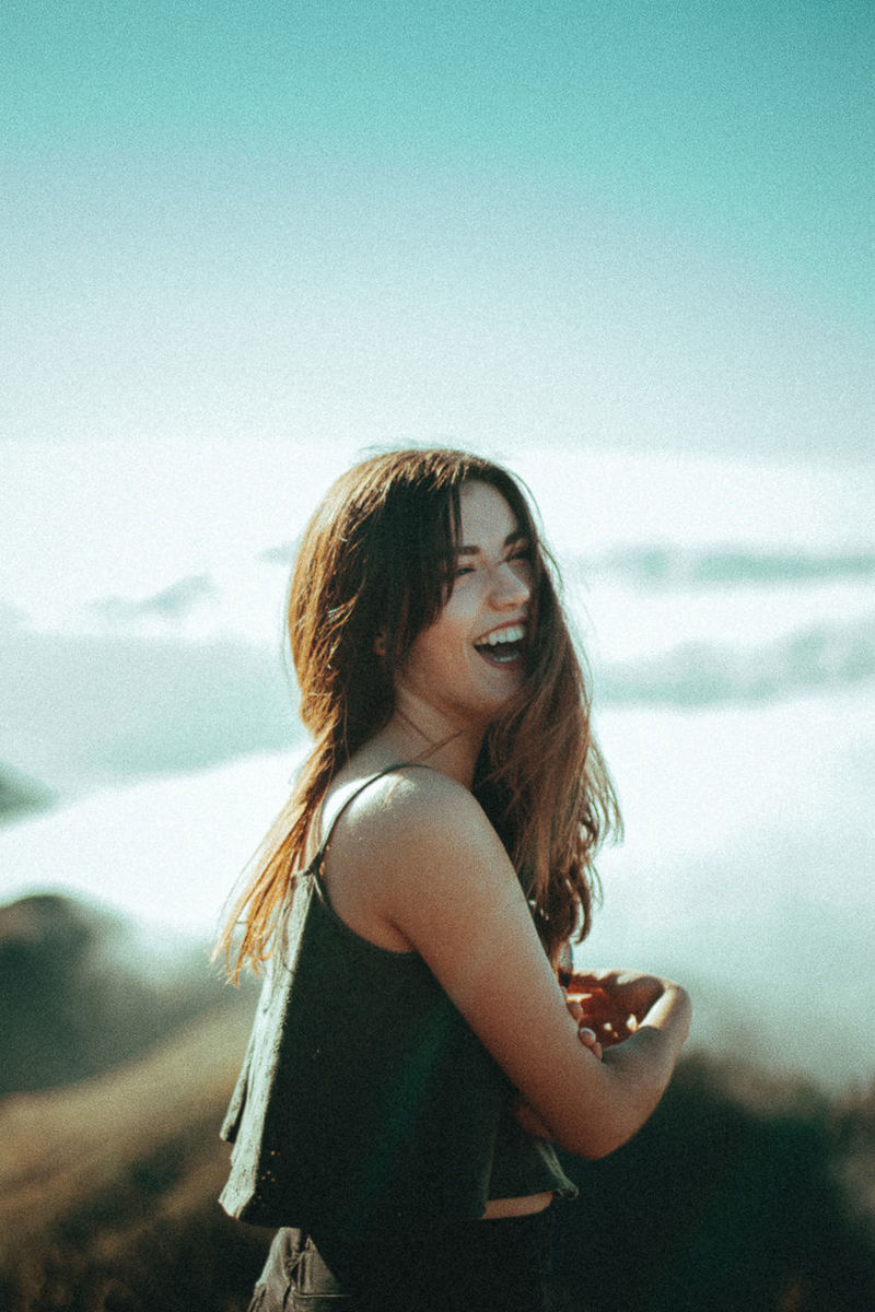 HAPPY WOMAN STANDING AGAINST SKY IN BACKGROUND