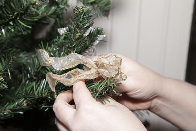 Close-up of hands decorating christmas tree