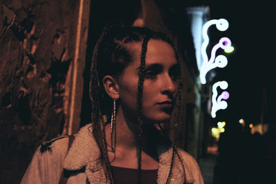 Woman with braided hair looking away outdoors during night