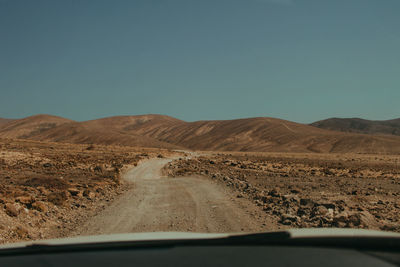 Scenic view of desert against clear sky seen through car windshield