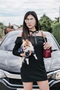 Young woman with dog standing against car