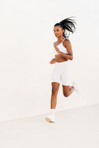 Portrait of young woman exercising against white background