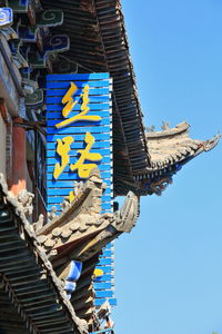 Low angle view of text on building against clear blue sky