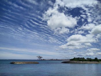 Scenic view of river against cloudy sky on sunny day