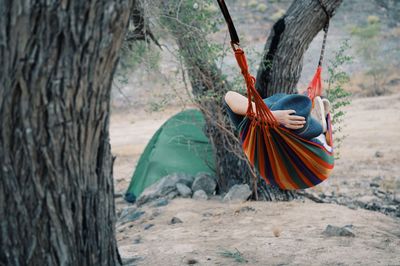 Rear view of woman hanging on a hammock with a green tent in a backgroun