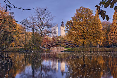 Arch bridge over lake by buildings against sky during autumn