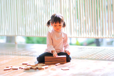 Full length of girl playing with wooden building blocks at home