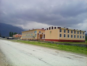 Empty road by buildings against sky