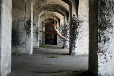 Full length of woman dancing in corridor of abandoned building