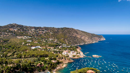 High angle view of townscape by sea against clear blue sky