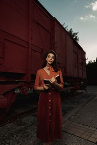 Portrait of young woman standing against sky