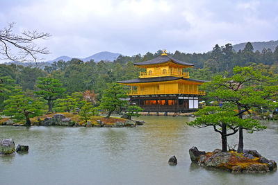 Built structure by lake and building against sky