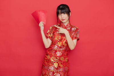Portrait of a smiling young woman against red background