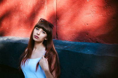 Portrait of young woman standing by building