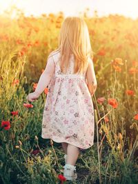 Rear view of woman with pink flowers on field