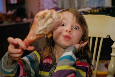 Portrait of cute girl holding chicken meat at restaurant