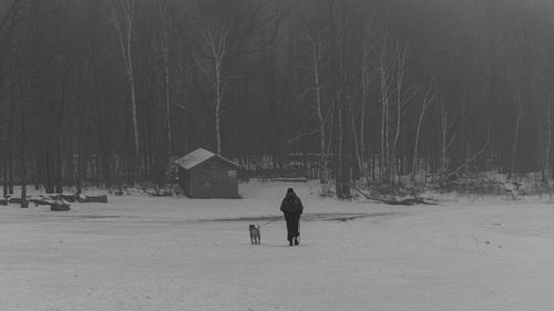 Rear view of man walking on snow covered landscape