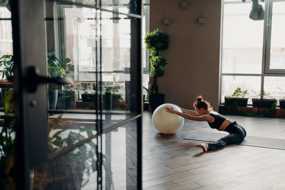 Full length of woman stretching while sitting at yoga studio